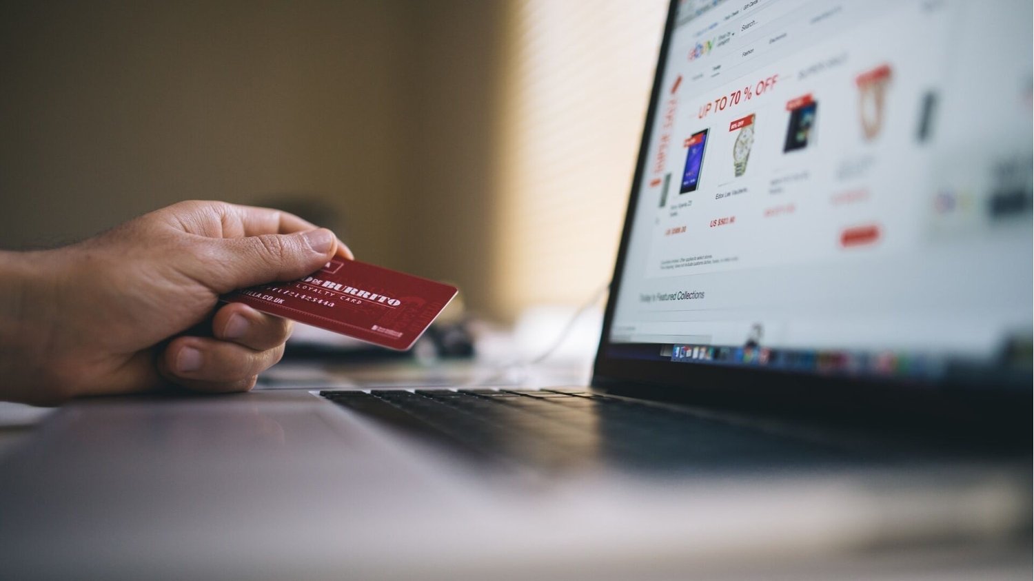 Person zückt Kreditkarte am Laptop während des Onlineshoppens am Black Friday